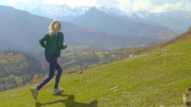 La cámara sigue a una joven hermosa mujer que corre cuesta arriba por una pendiente — Vídeos de Stock