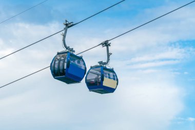 Gökyüzü ve bulutların yanındaki teleferiğin iki taksisine yakın çekim, füniküler