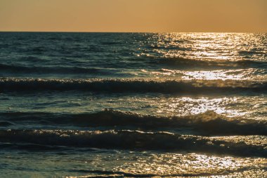 Gün batımında denizde dalgaların yakın çekimi, güneş ışığı yolu. Güzel doğal arkaplan
