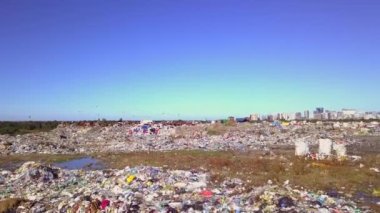 Şehir çöplüğünün insansız hava aracı görüntüsü deniz, şehir ve dağların arka planında.