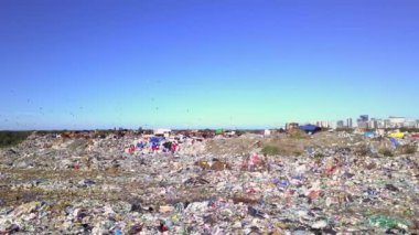 Şehir çöplüğünün insansız hava aracı görüntüsü deniz, şehir ve dağların arka planında.