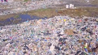 Şehir çöplüğünün insansız hava aracı görüntüsü deniz, şehir ve dağların arka planında.