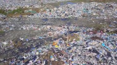 Şehir çöplüğünün insansız hava aracı görüntüsü deniz, şehir ve dağların arka planında.