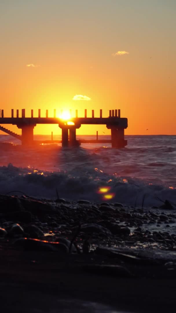 Hot storm waves hit the pier at sunset. Beautiful orange sky, crashing waves. — Video Stock
