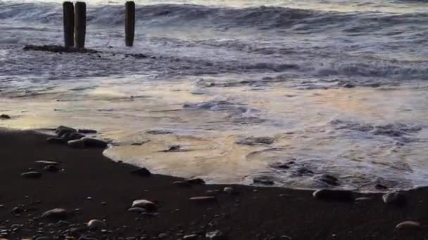 Wellen krachen bei Sonnenuntergang gegen alte Stahlbetonpfeiler am Strand — Stockvideo