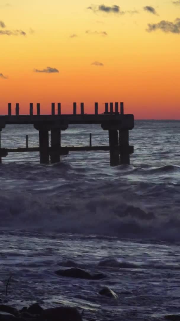 人々のシルエットが歩く桟橋の裏に沈む夕日. — ストック動画