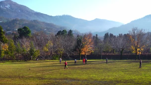 Local children in village play football against backdrop of mountains. — Vídeo de Stock