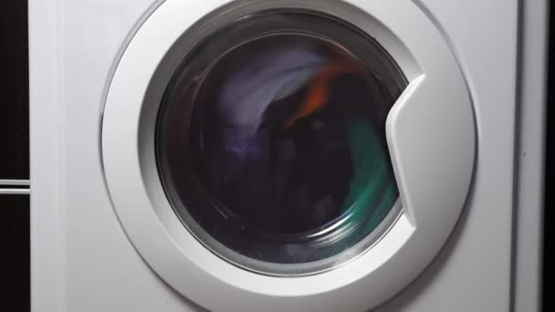 Close-up of a washing machine washing colored clothes. — стоковое видео