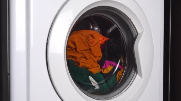 Κοντινό πλάνο ενός πλυντηρίου ρούχων που πλένει χρωματιστά ρούχα. — Αρχείο Βίντεο