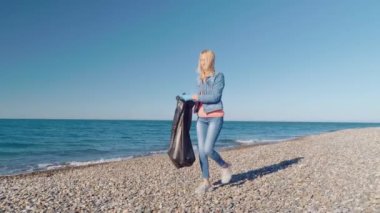 Bir kadın gönüllü siyah bir çöp torbasında çöp topluyor..