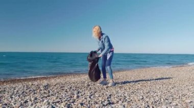 Plajda plastik şişe toplayan bir kadın.,