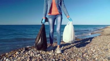 Kadın kameranın önünde, arka planda çöp torbalarıyla poz veriyor..