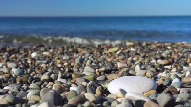 A woman's hand makes a pyramid of stones on the background of the sea or ocean. — Vídeo de Stock