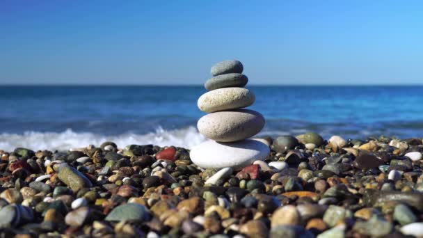 Piramis kövek a tengerparton egy napsütéses napon a kék tenger háttér. — Stock videók