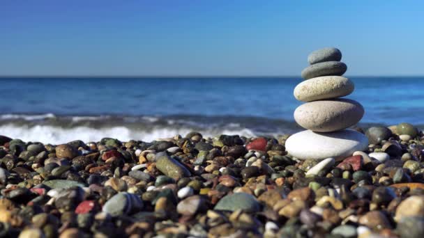 Kamienie piramidy na wybrzeżu w słoneczny dzień na błękitnym tle morza. — Wideo stockowe