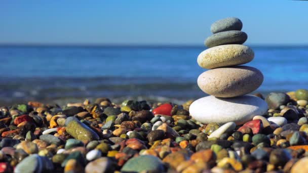 Pyramid stones on the seashore on a sunny day on the blue sea background. — 图库视频影像