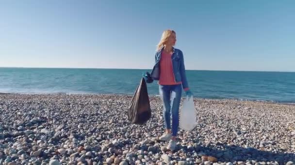 En kvinna samla rengöring plastflaskor på stranden, — Stockvideo