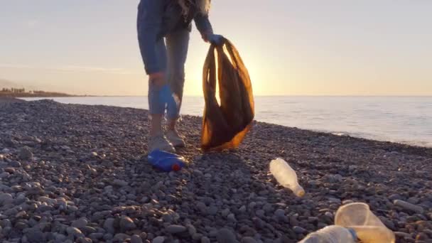 Μια εθελόντρια μαζεύει σκουπίδια σε μια μαύρη σακούλα σκουπιδιών.. — Αρχείο Βίντεο