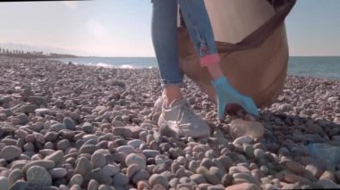 Plajda plastik şişe toplayan bir kadın.,