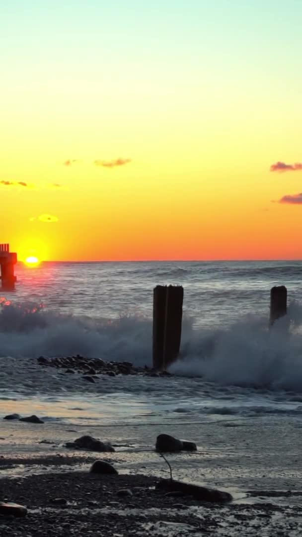 Waves crash against old reinforced concrete pillars on the beach at sunset — Video Stock