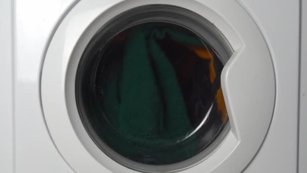 Close-up of a washing machine washing colored clothes. — 图库视频影像