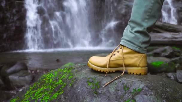 De hand van een man bindt zijn veters tegen de achtergrond van een waterval.. — Stockvideo