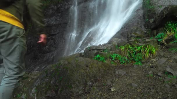 Hombre con mochila en la espalda es caminar solo a la cascada en las profundidades de la selva. — Vídeos de Stock