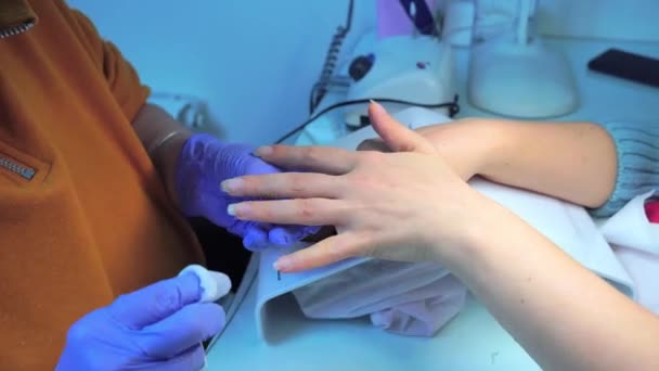 Hands of manicure master in blue gloves use an electric nail file remove cuticle — Video Stock