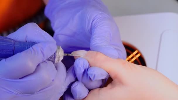 ब्लू दस्ताने में मैनीक्योर मास्टर के हाथ एक इलेक्ट्रिक नेल फ़ाइल छल्ली हटाने का उपयोग करते हैं — स्टॉक वीडियो