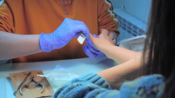 Close-up of manicure master in blue gloves filing nails with special nail file — Vídeo de Stock
