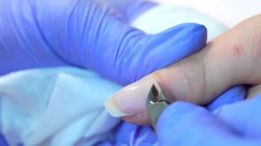 Close-up of manicure master doing a manicure to woman, cutting off the cuticle