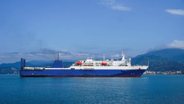 Huge passenger car-railway ferry enters the city against the backdrop of mountains on a sunny day, Batumi, Georgia