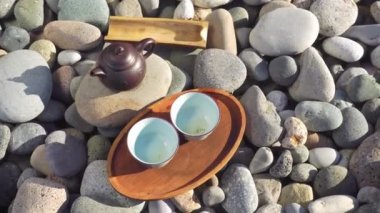 Close-up of two empty cups on a wooden tray, a brown teapot,