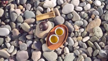 Close-up of two poured cups of tea on a wooden tray, brown teapot,