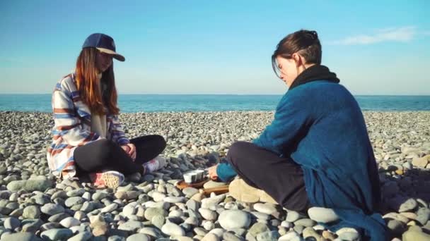 Two women are preparing for tea ceremony. sitting in lotus position on seashore. — Wideo stockowe