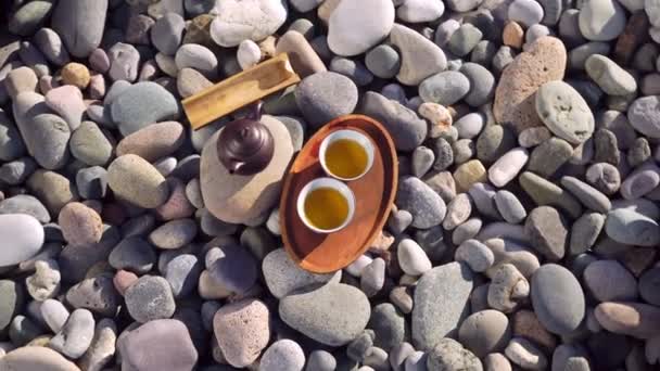 Close-up de duas xícaras derramadas de chá em uma bandeja de madeira, bule marrom, — Vídeo de Stock