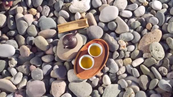 Close-up of two poured cups of tea on a wooden tray, brown teapot, — Stok video