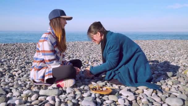 Two women are sitting on the seashore and preparing for a rape ceremony. — ストック動画