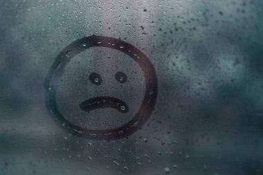 Yağmurdan gelen nemli camlara elle çizilmiş hüzünlü gülümseme, boşluğu kopyala. Yalnızlık, üzüntü, kötü hava kavramı