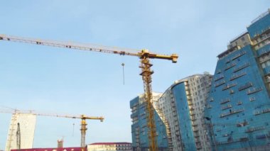 Gökdelenlerin ve mavi gökyüzünün arka planında vinçler olan inşaat alanı.