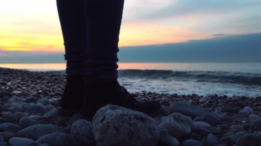 Kadın ayağı, bot ve kot giymiş, sahilde, denize karşı