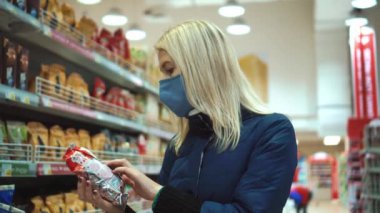 Bir kadın süpermarkette bir paket cips seçer. Mağazadan alışveriş..