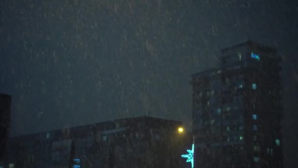 Uma forte queda de neve. Neve caindo no fundo do edifício. Cidade noturna — Vídeo de Stock