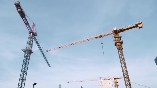 Cantiere con gru sullo sfondo di grattacieli e cielo blu. — Video Stock