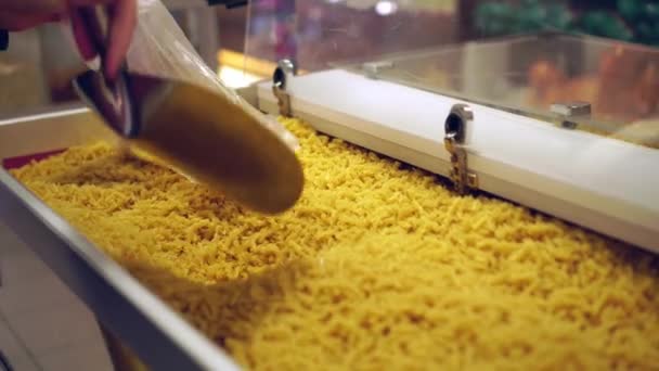 Kvinnans hand lägger pasta i påse i snabbköpet med en järnspatel. — Stockvideo