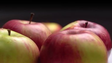 Taze kırmızı elmalar siyah arka planda bir tabakta dönüyorlar..