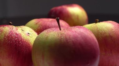 Taze kırmızı elmalar siyah arka planda bir tabakta dönüyorlar..