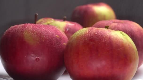 Verse zoete rode appels draaien op een bord op een zwarte achtergrond. — Stockvideo