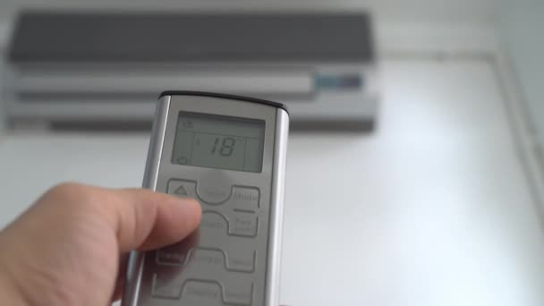 A mão pressionando o controle remoto reduz a temperatura do condicionador de ar. — Vídeo de Stock