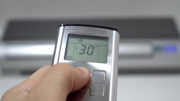 La mano presionando el mando a distancia reduce la temperatura del aire acondicionado. — Vídeo de stock